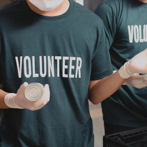 People boxing cans wearing a t-shirt that says, "Volunteer."