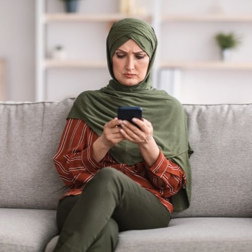 A woman frowning while scrolling on her smartphone.