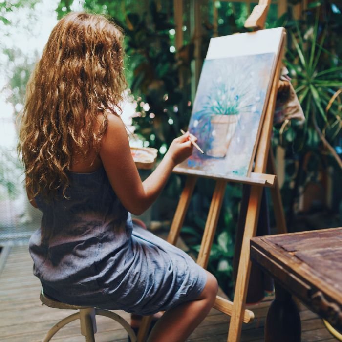 A person painting a plant on a canvas on an easel