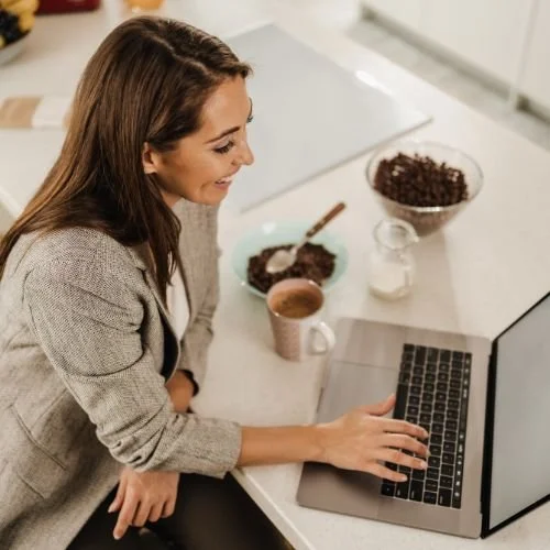 Woman using a laptop. She is smiling.
