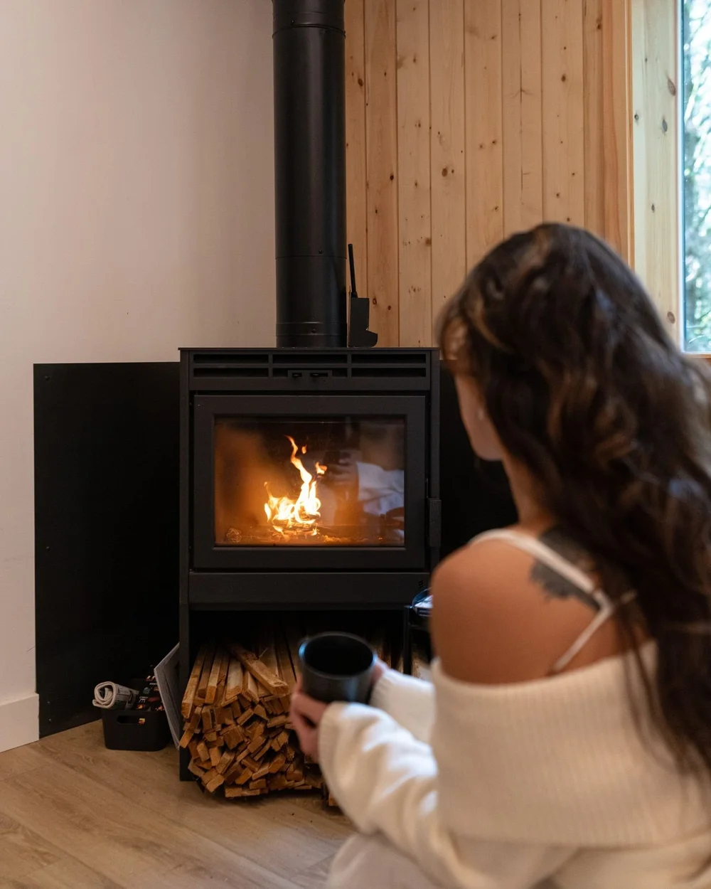 Black wood stove with firewood stacked beside it