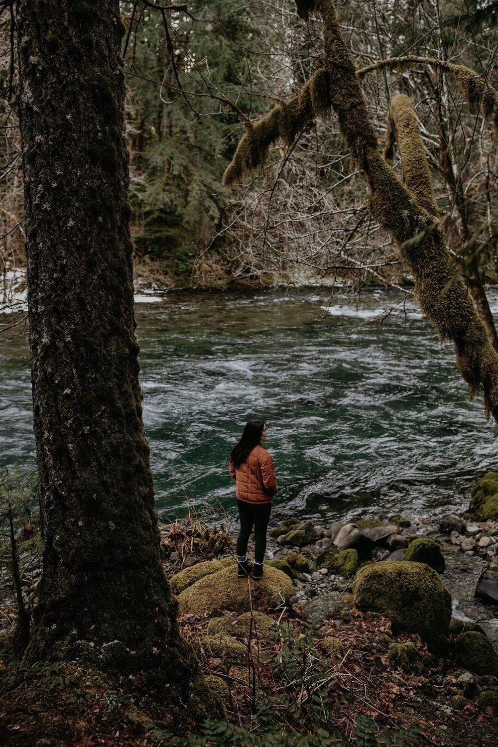 A guest standing on the rocks at the river’s edge at the end of the trail