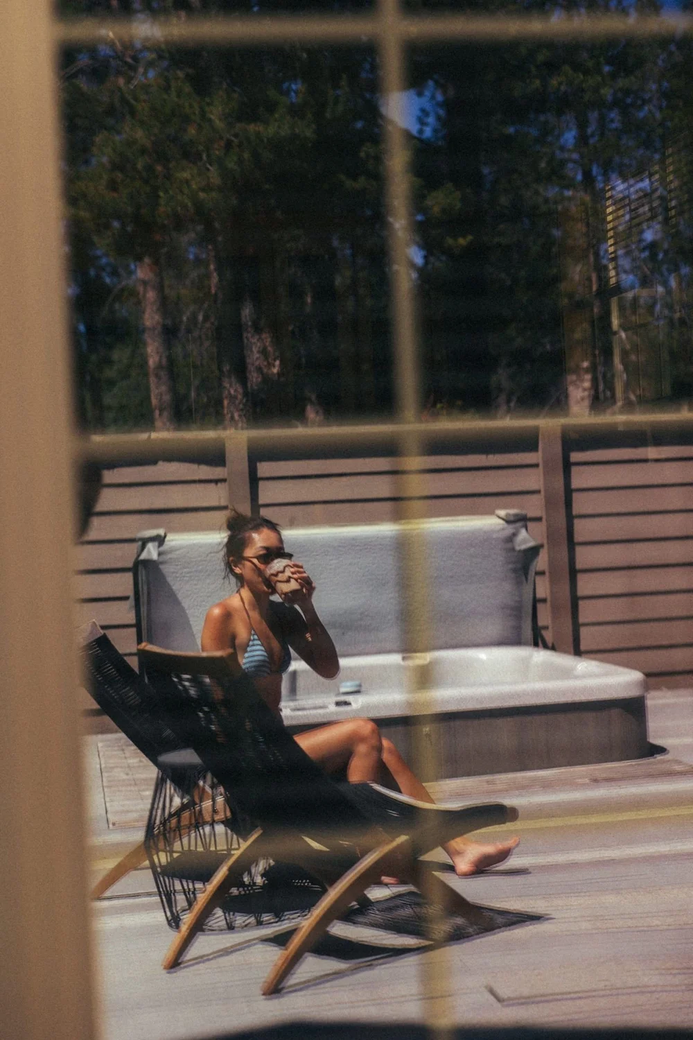 Relaxing on the back deck by the hot tub, seen through the window