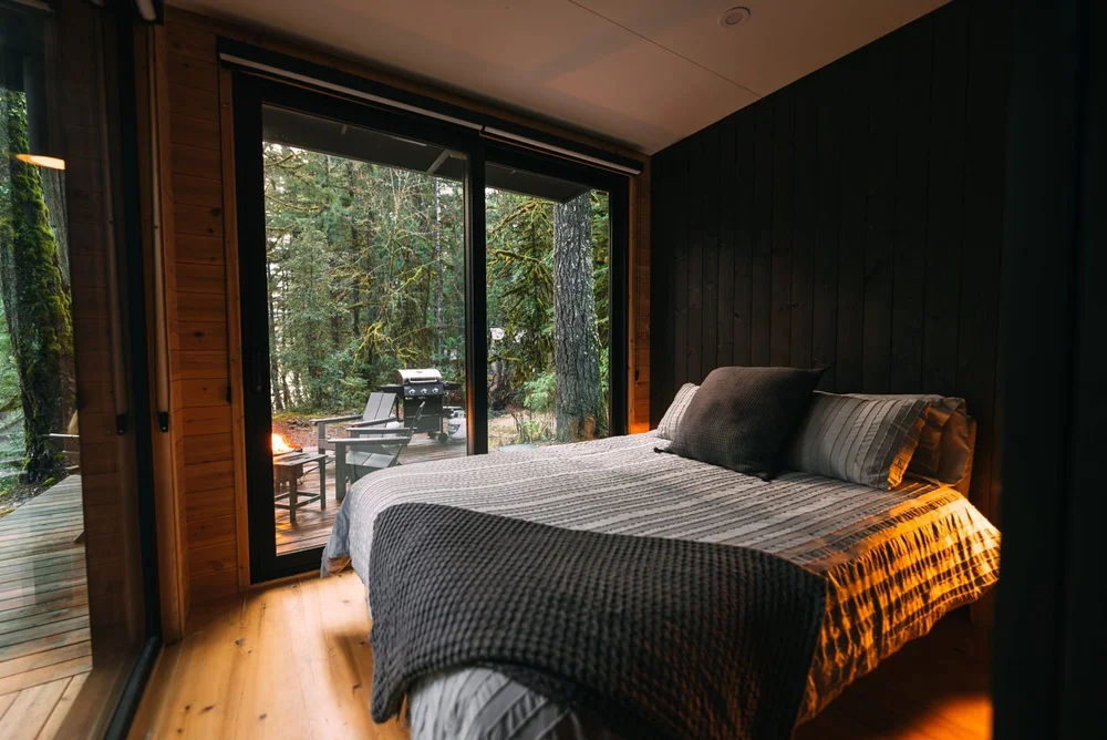 Bedroom with a picture window looking into the forest