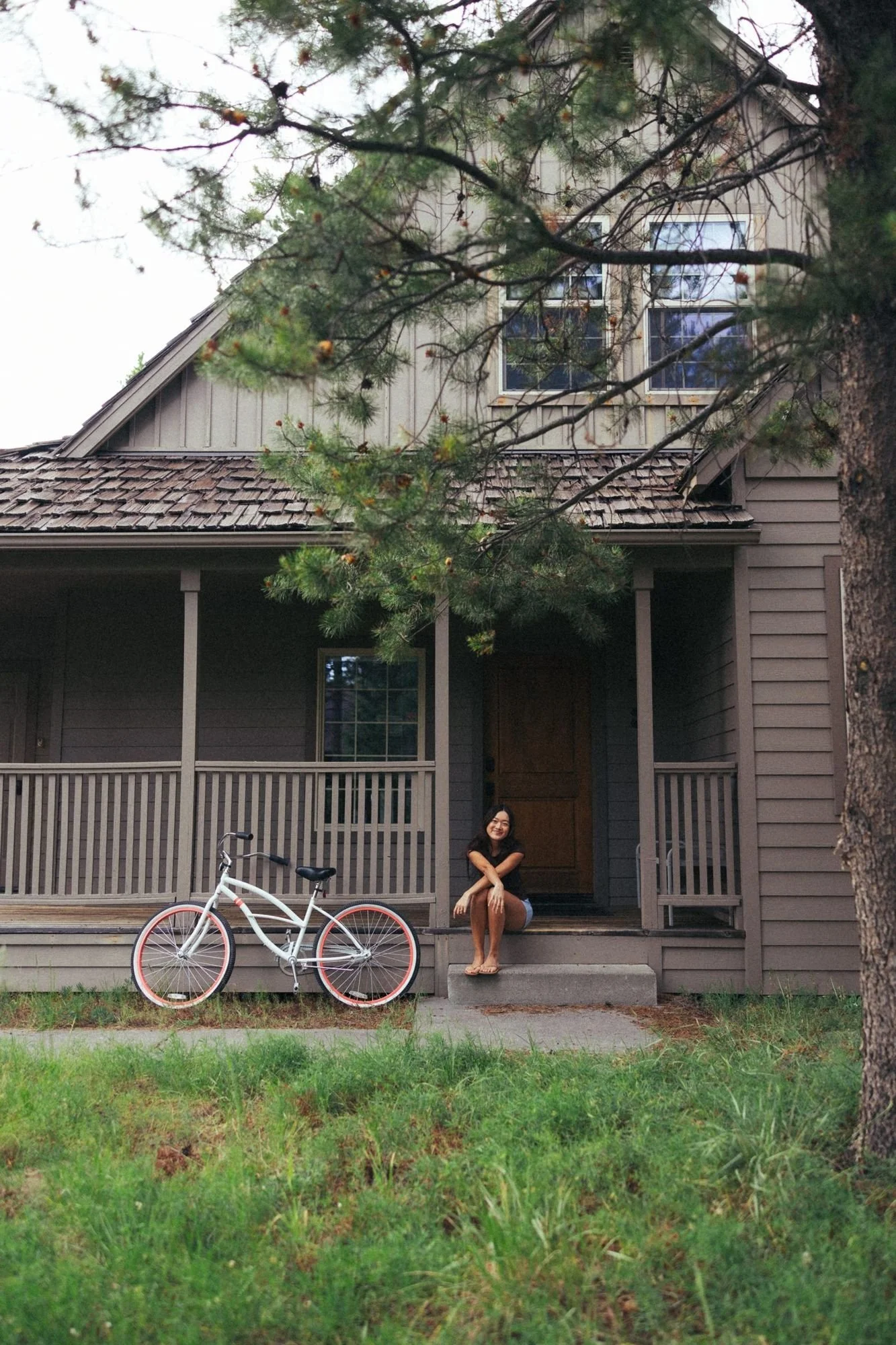 A guest resting on the front porch steps with a cruiser bike