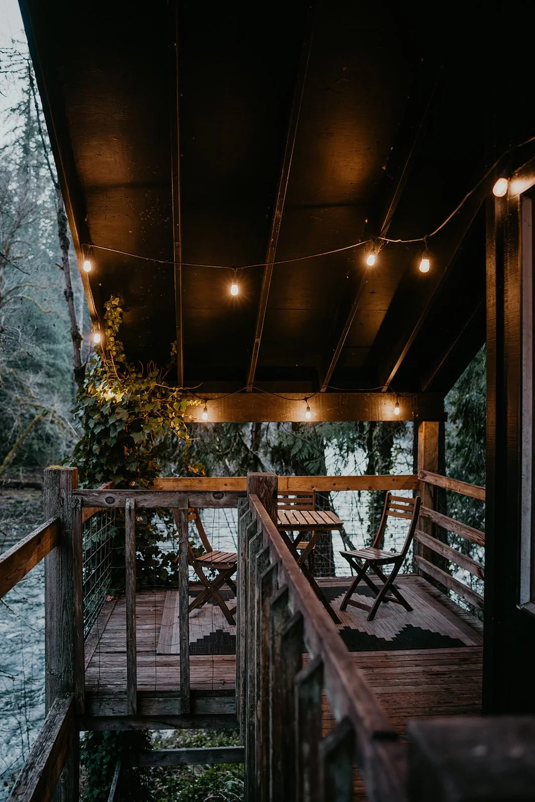 The covered upper deck at night with string lights over the river