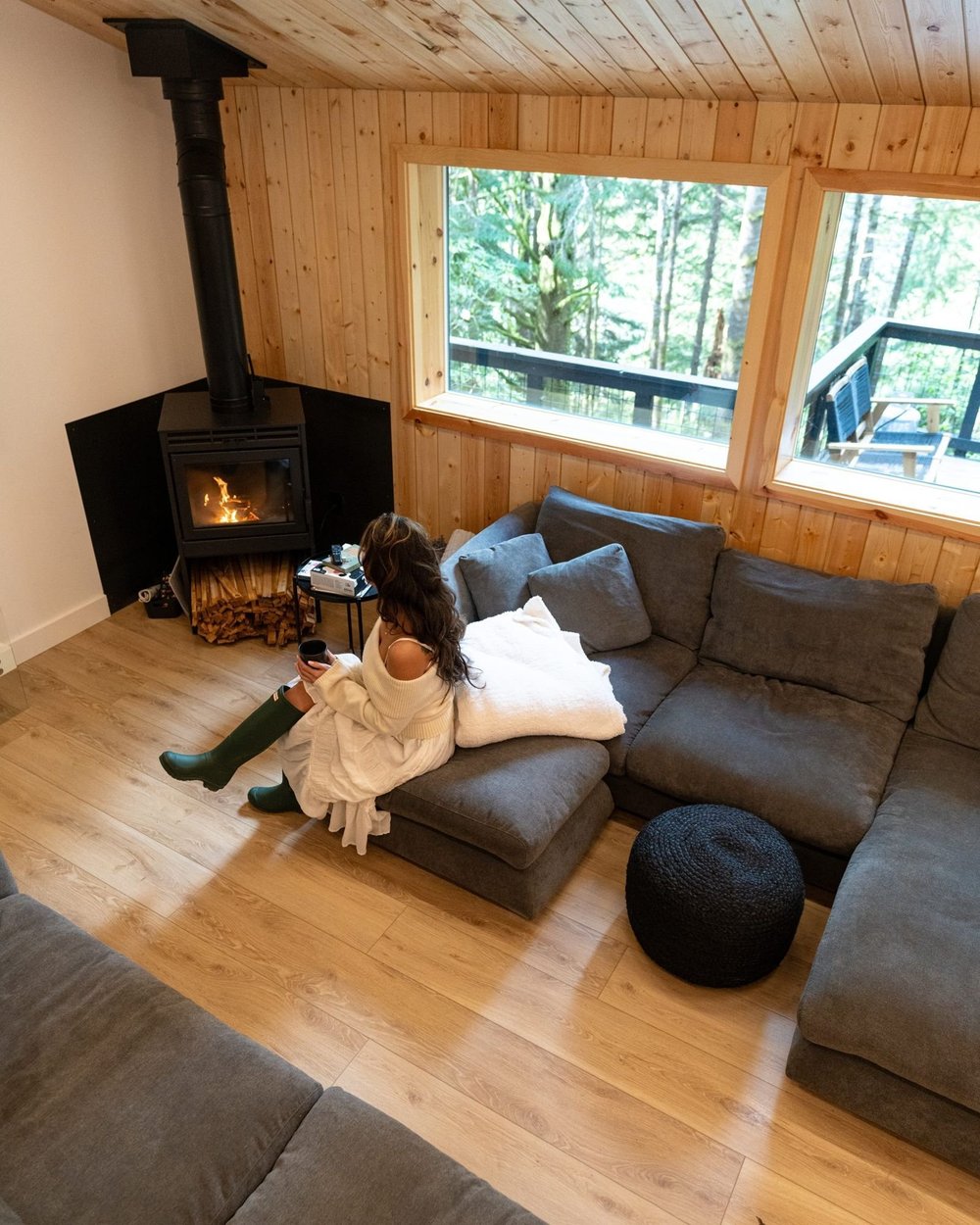 Oversized sectional beside the wood stove and forest windows