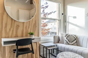 The Nordic suite, with a plywood accent wall, round mirror and a desk by the window