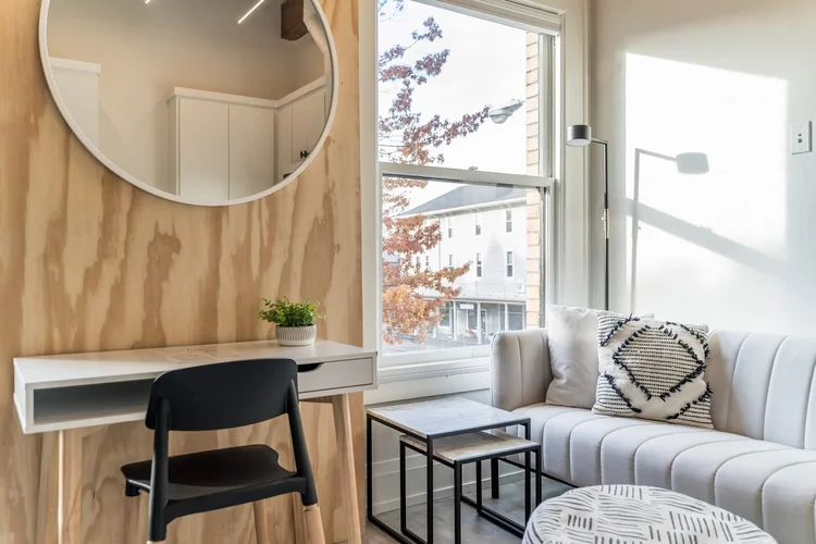 The Nordic suite, with a plywood accent wall, round mirror and a desk by the window
