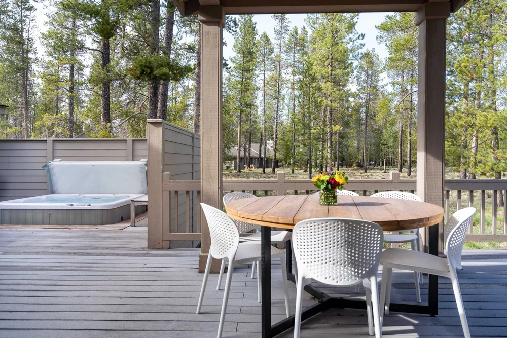 Back deck with a round dining table beside the private hot tub