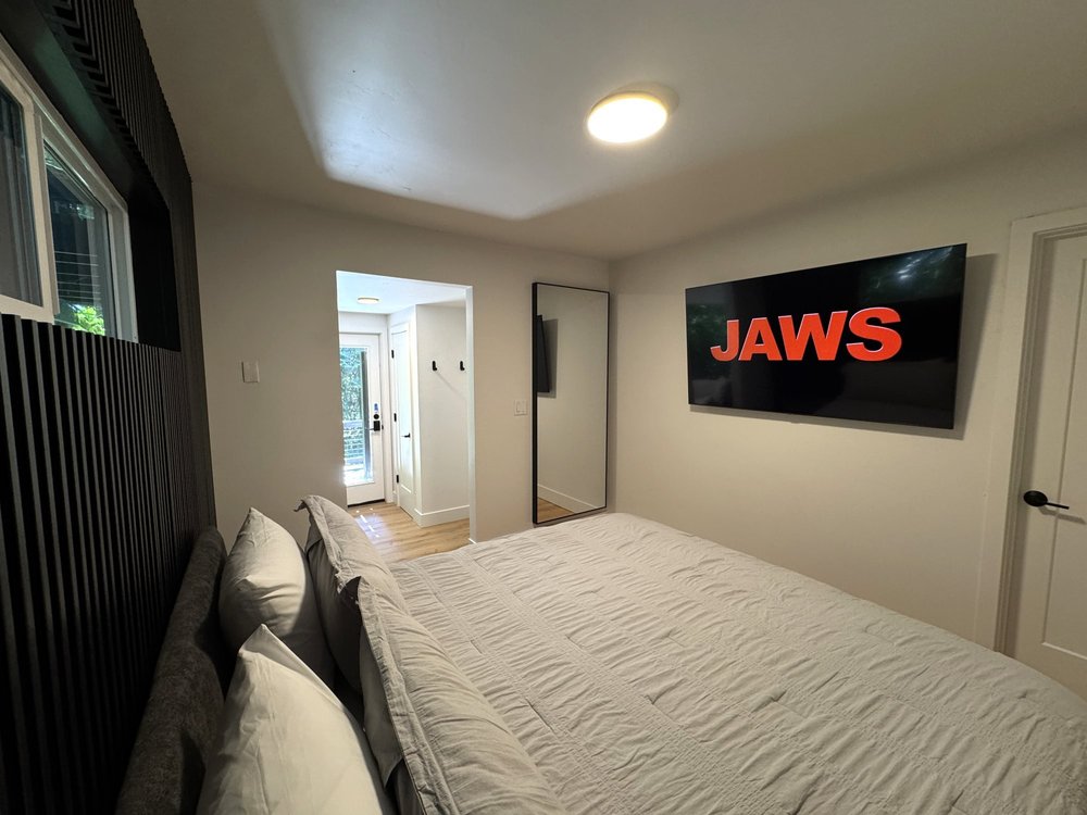 King bed in bedroom 1 with a black slat wall and a wall-mounted TV