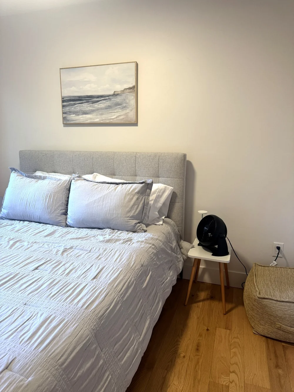 Queen bed with white linens and coastal art