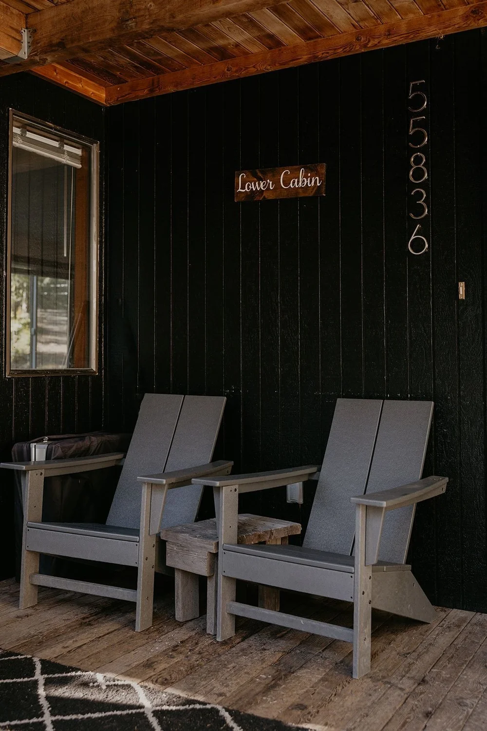 Two chairs on the covered porch beside the Lower Cabin sign