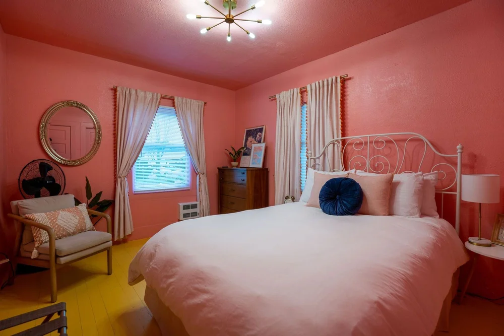Coral pink queen bedroom with a white iron bed