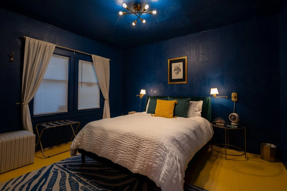 Navy blue queen bedroom with a gold pillow