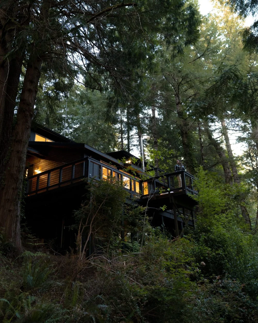 The dark lake house tucked into the forest at dusk