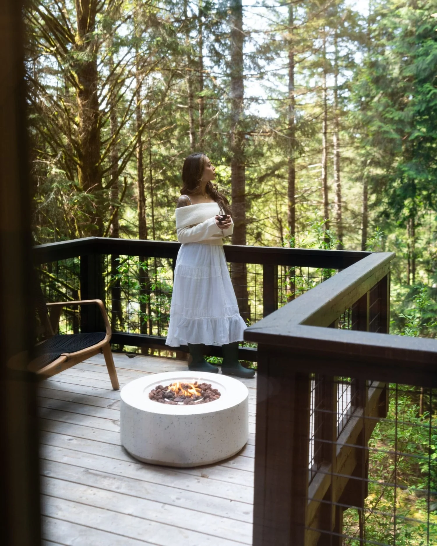 A guest on the wraparound deck by the fire pit, high among the firs