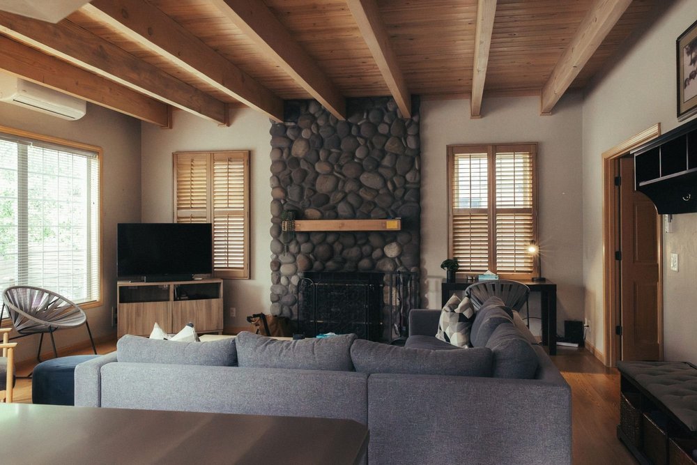 Living room with a river-rock fireplace and wood-beamed ceiling