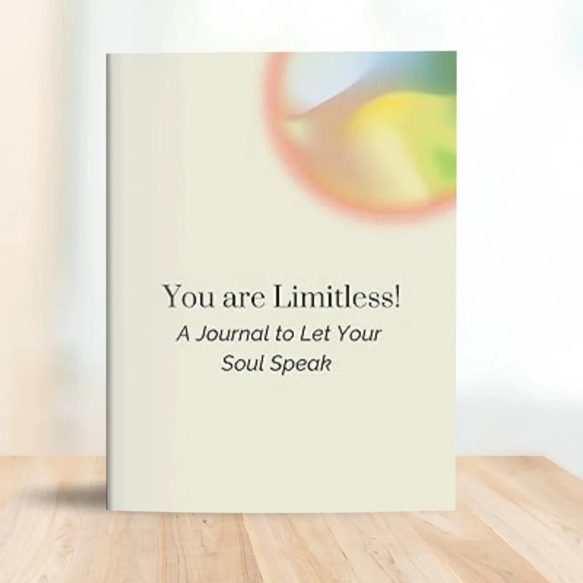 A book titled "You are Limitless!" with the subtitle "A Journal to Let Your Soul Speak," standing on a wooden floor with a white background. The cover features a blurred, colorful circle at the top.