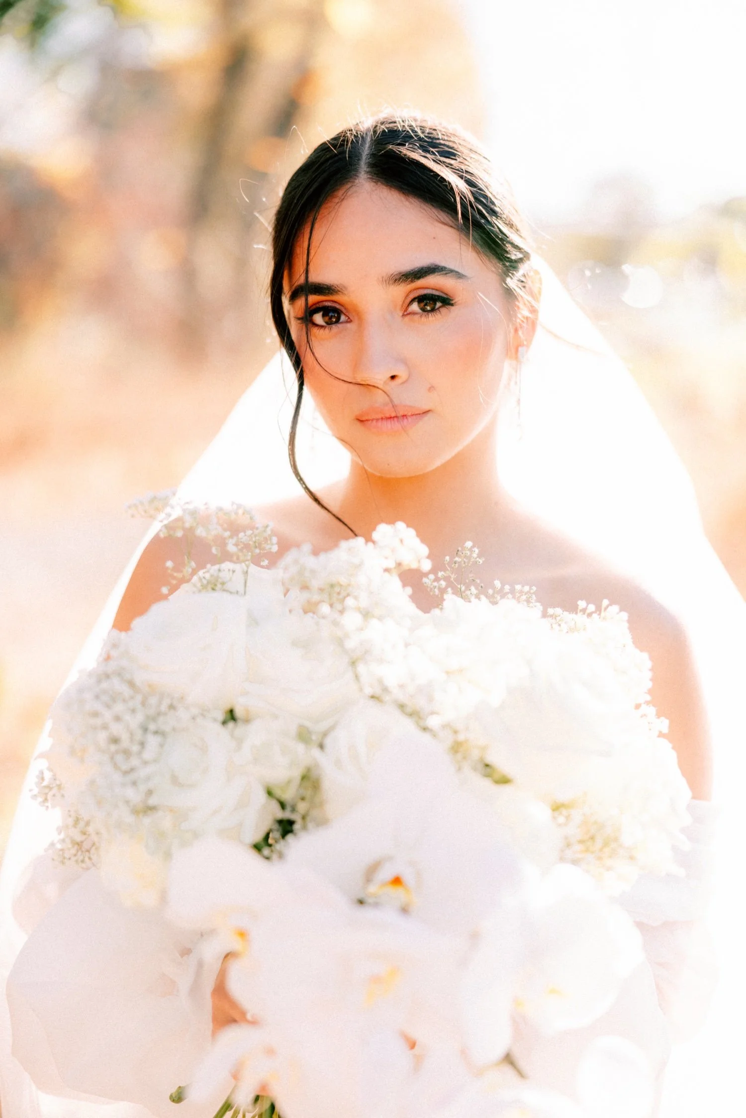 timeless photograph of bride looking into the camera holding her white bouquet by mira mira florals on her wedding day at the roundhouse