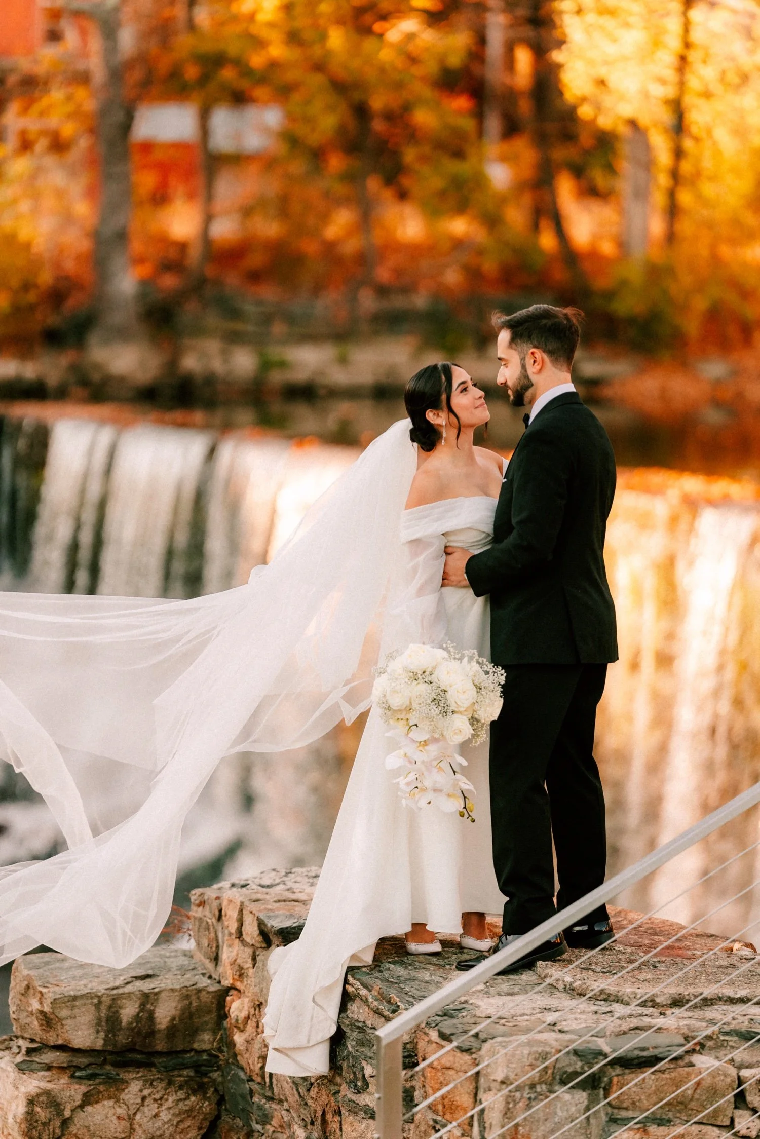 bride and groom look at each other in front of beacon falls during their autumn wedding at the roundhouse