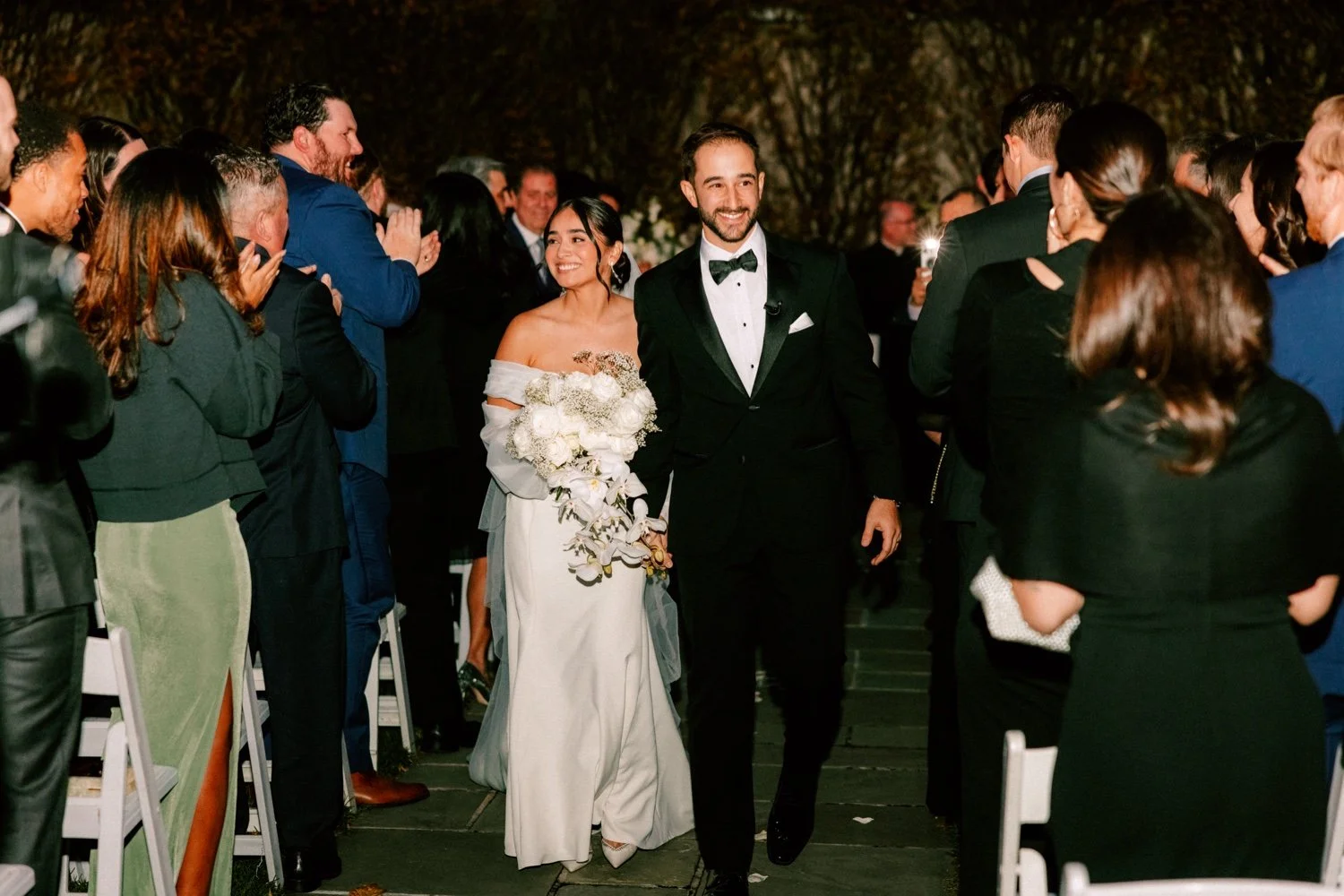 bride and groom walk down the aisle with flash photographs during their november wedding ceremony at the roundhouse