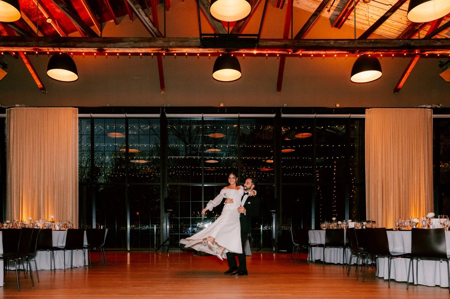 groom lifts bride while they practice their first dance in the reception room at the roundhouse