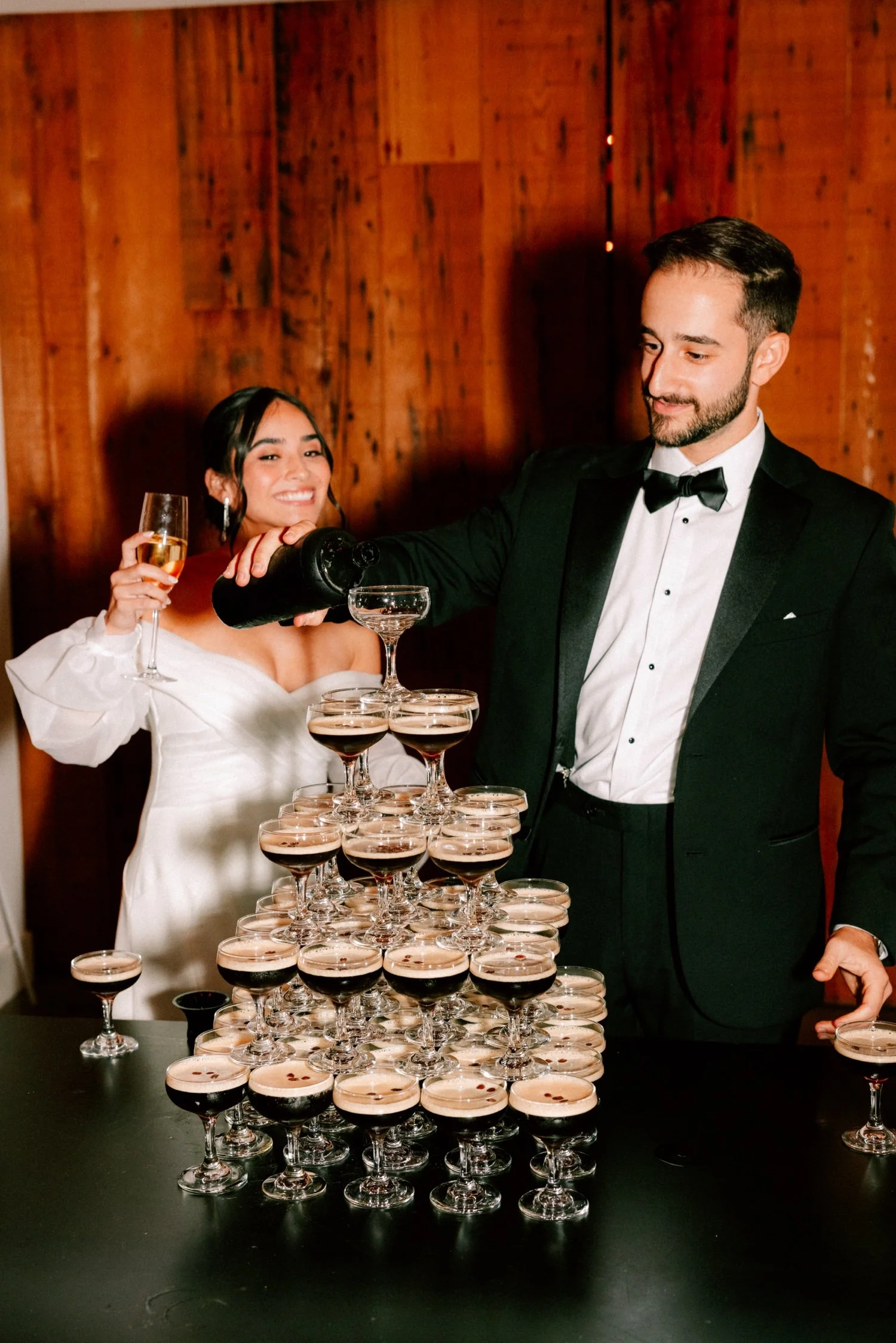 groom pours espresso martini over tower while bride watches during cocktail hour at the roundhouse