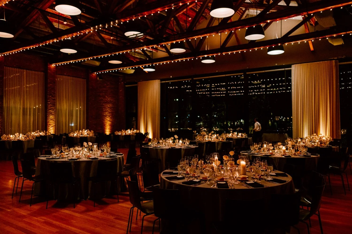 photograph of reception space with candlelight and white flowers by mira mira florals and uplighting by lnj events at the roundhouse