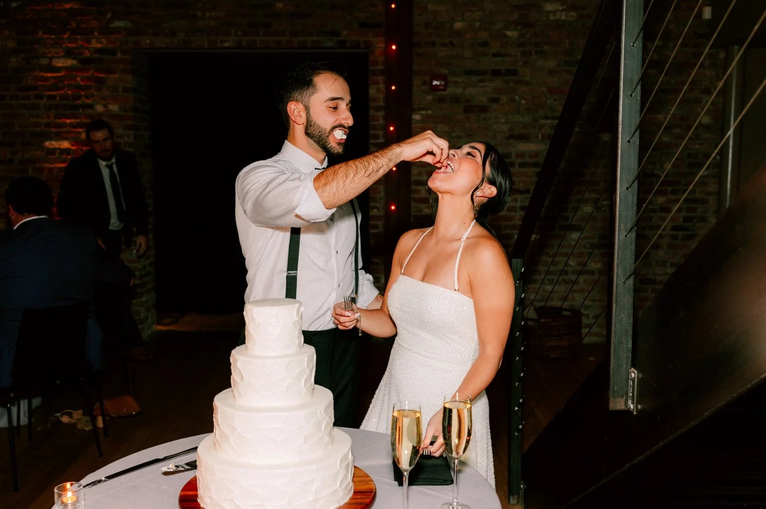groom feeds bride during their cake cutting at the roundhouse