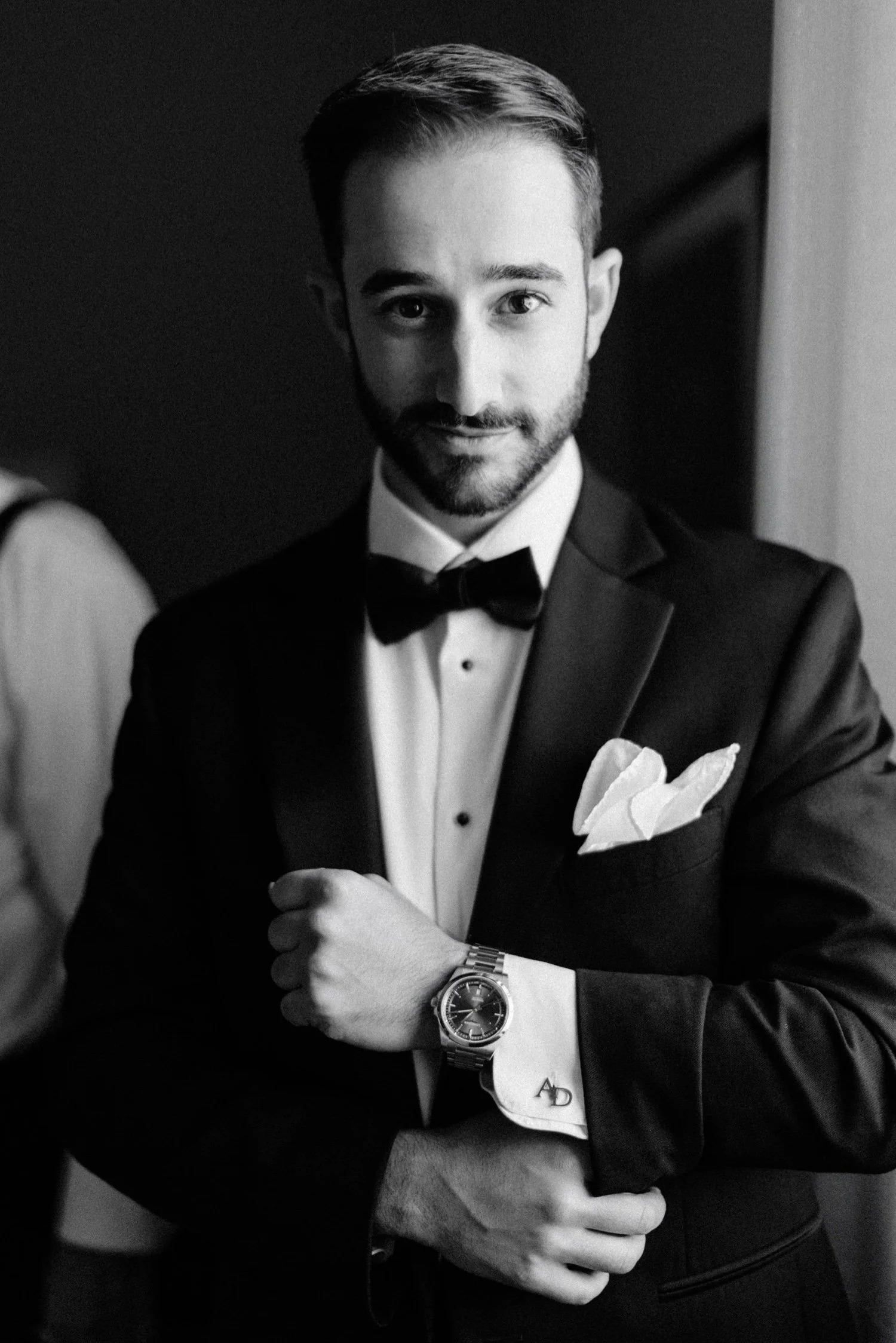black and white photograph of groom after getting dressed for his wedding day at the roundhouse