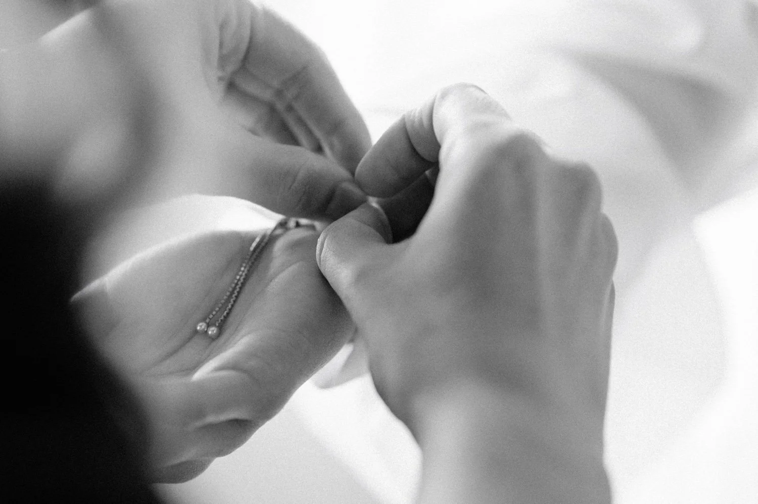 black and white detail photograph of mom putting on brides bracelet during wedding day at the roundhouse