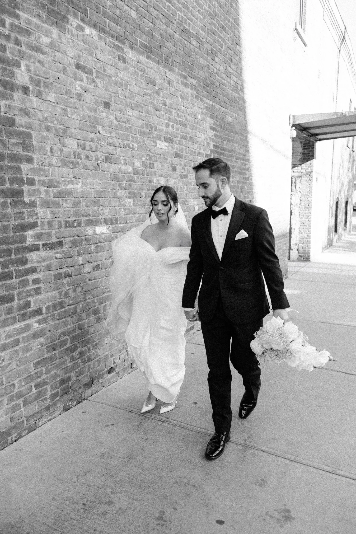 documentary black and white photograph of bride and groom walking down the street on their wedding day at the roundhouse