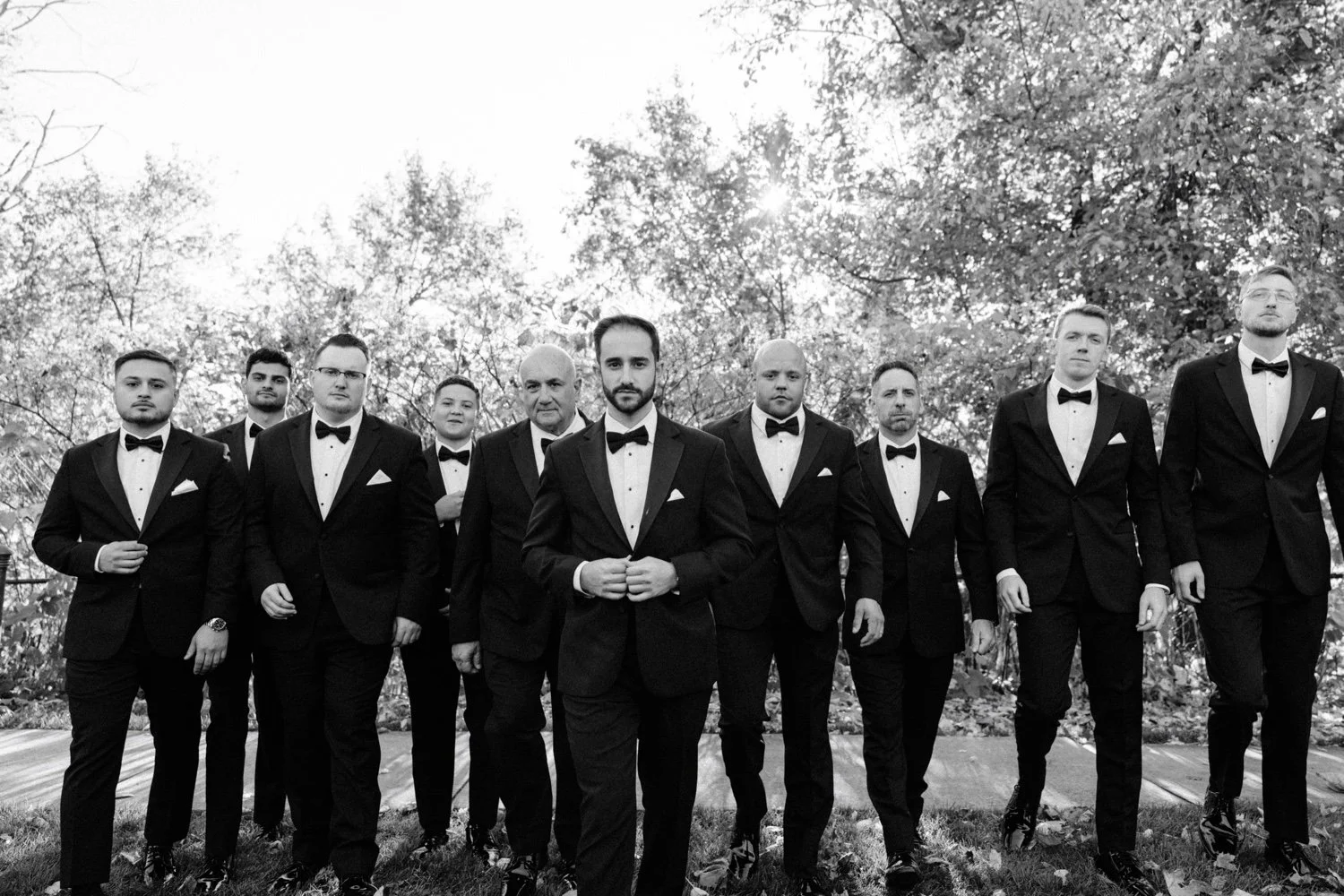 timeless black and white photograph of groom and groomsmen walking towards camera during november wedding at the roundhouse