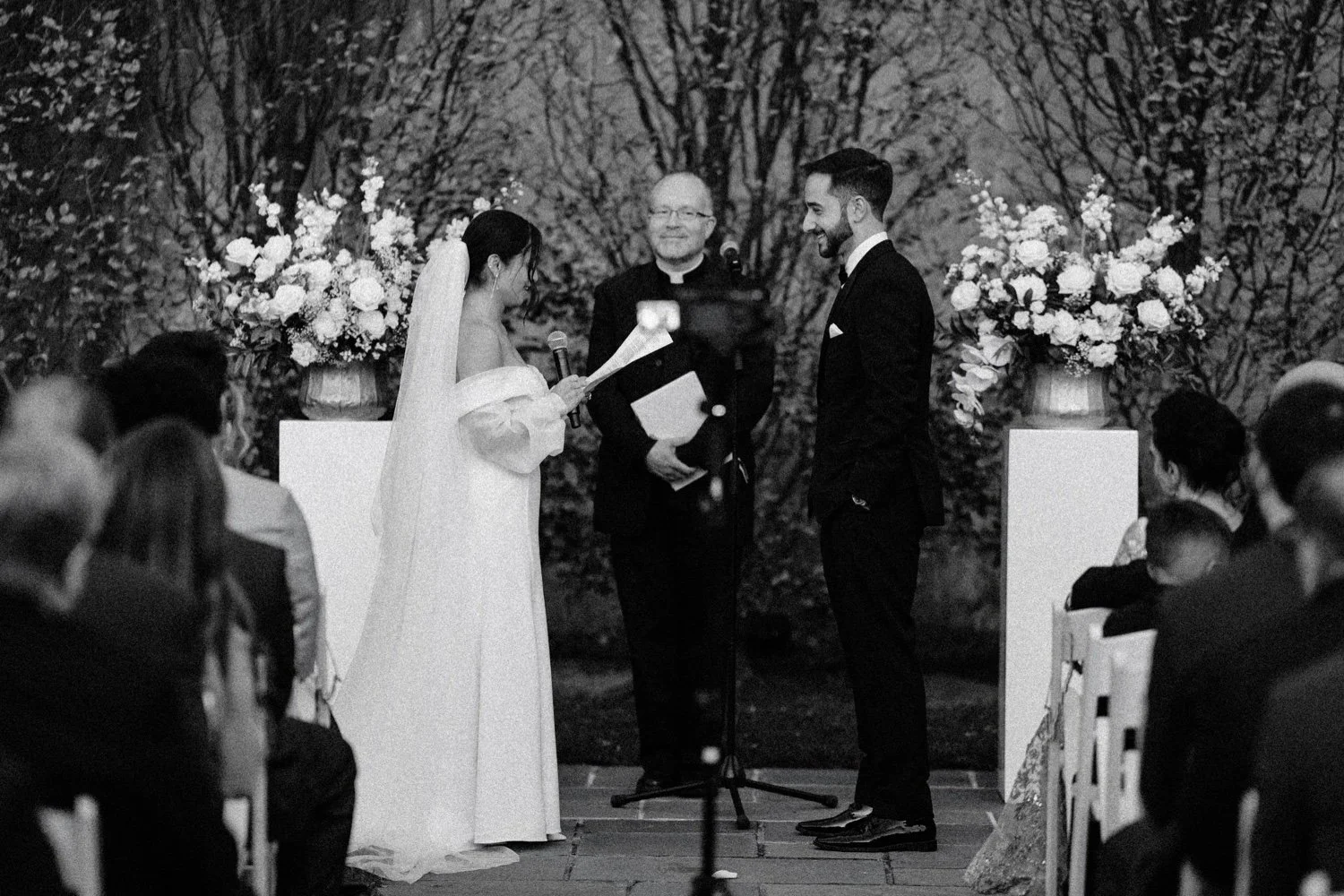 black and white photograph of bride saying vows to groom during outdoor wedding ceremony in november at the roundhouse