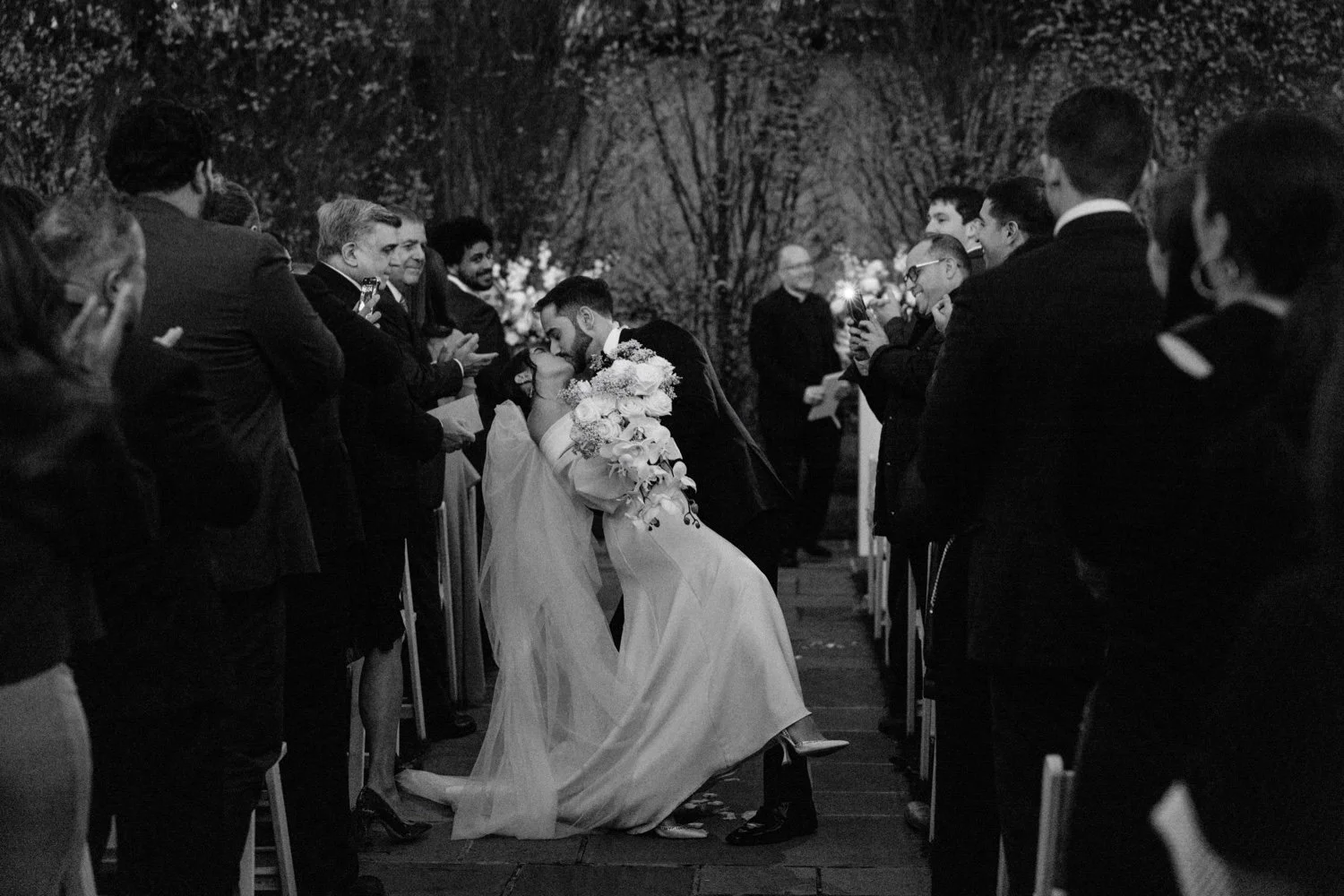black and white photograph of dip and kiss while walking down the aisle during november wedding ceremony at the roundhouse