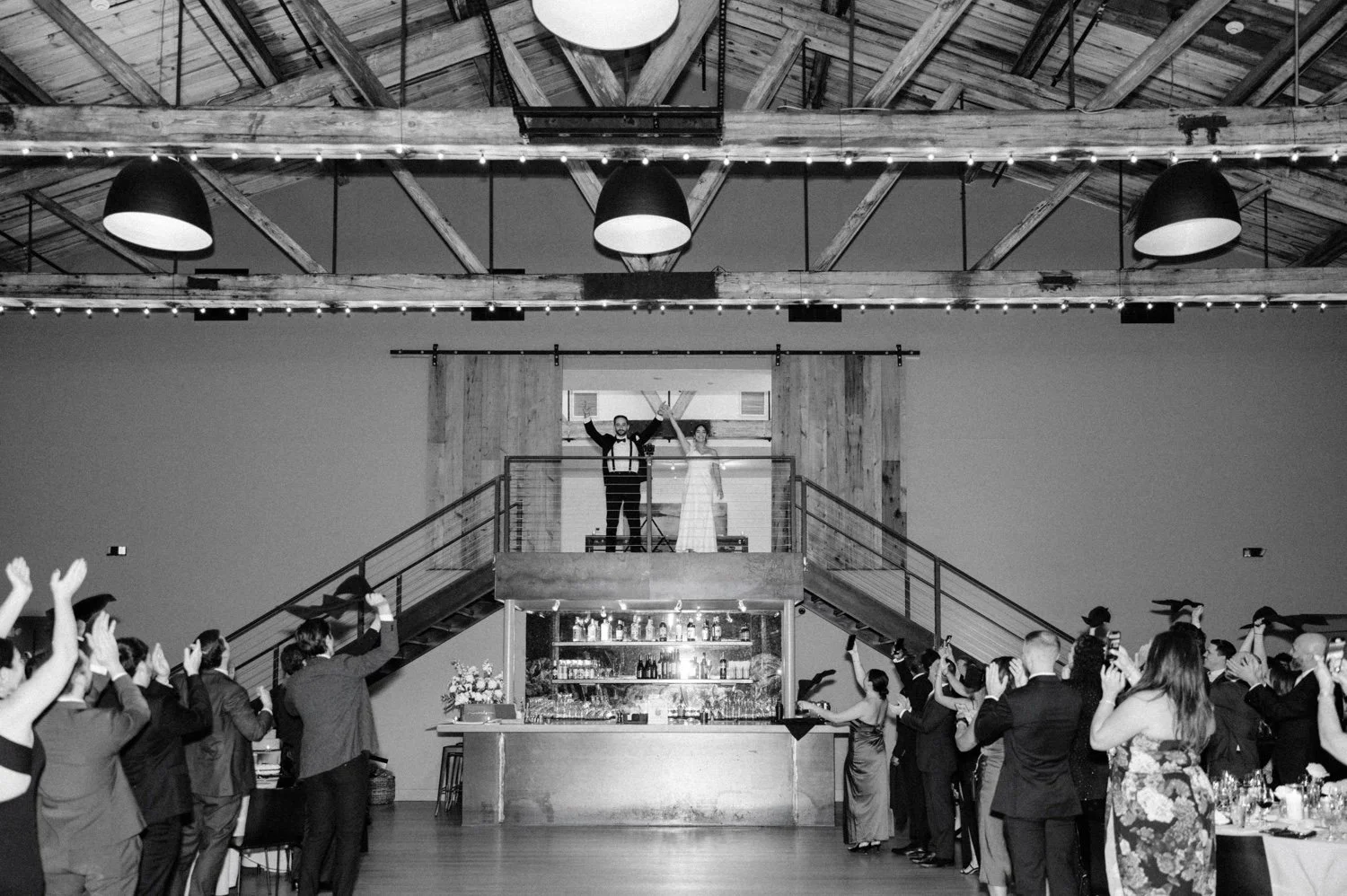 black and white photograph of couples grand intro through the barn doors during wedding reception at the roundhouse