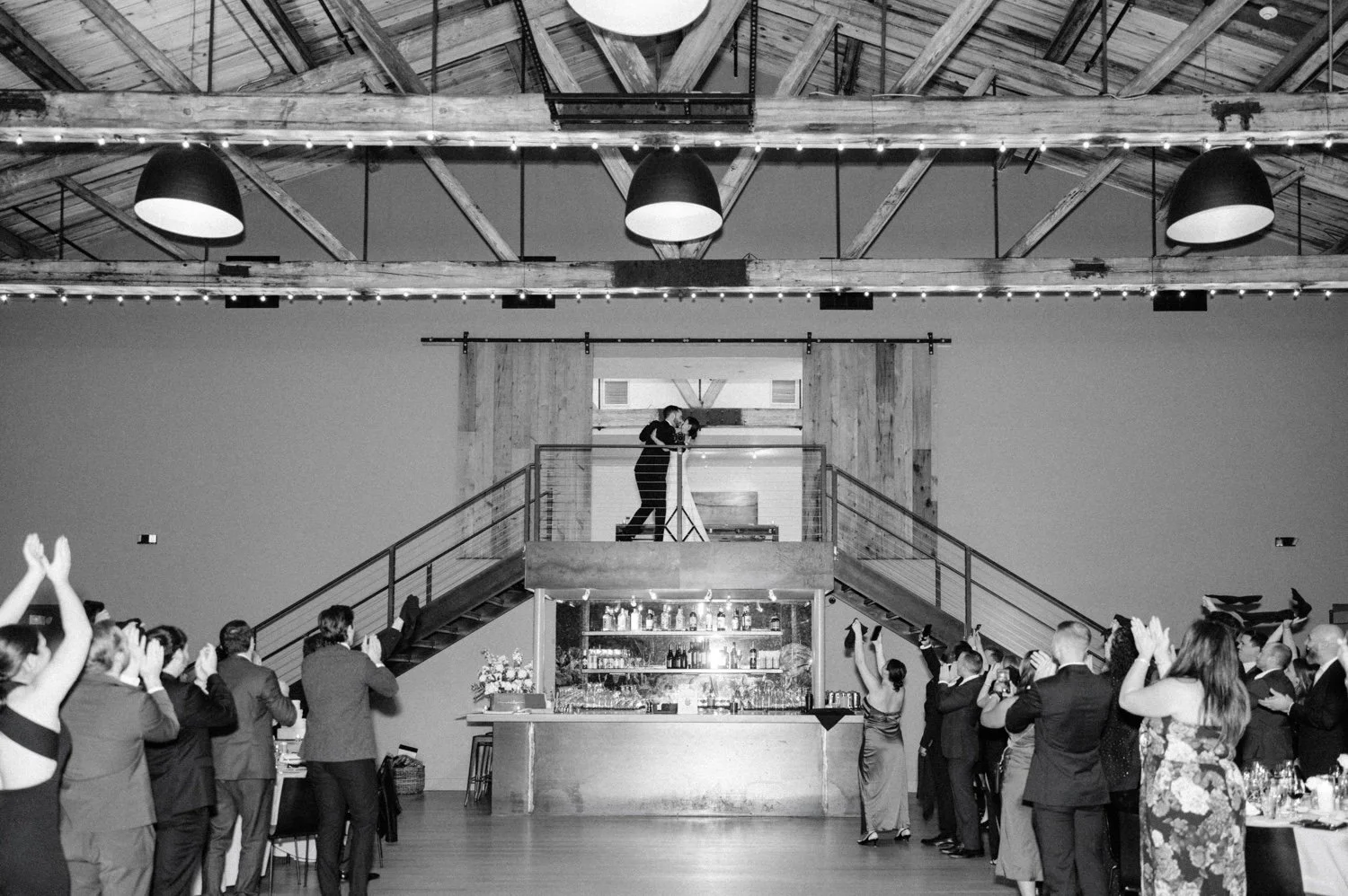 black and white photograph of couples grand entrance through the barn doors during wedding reception at the roundhouse