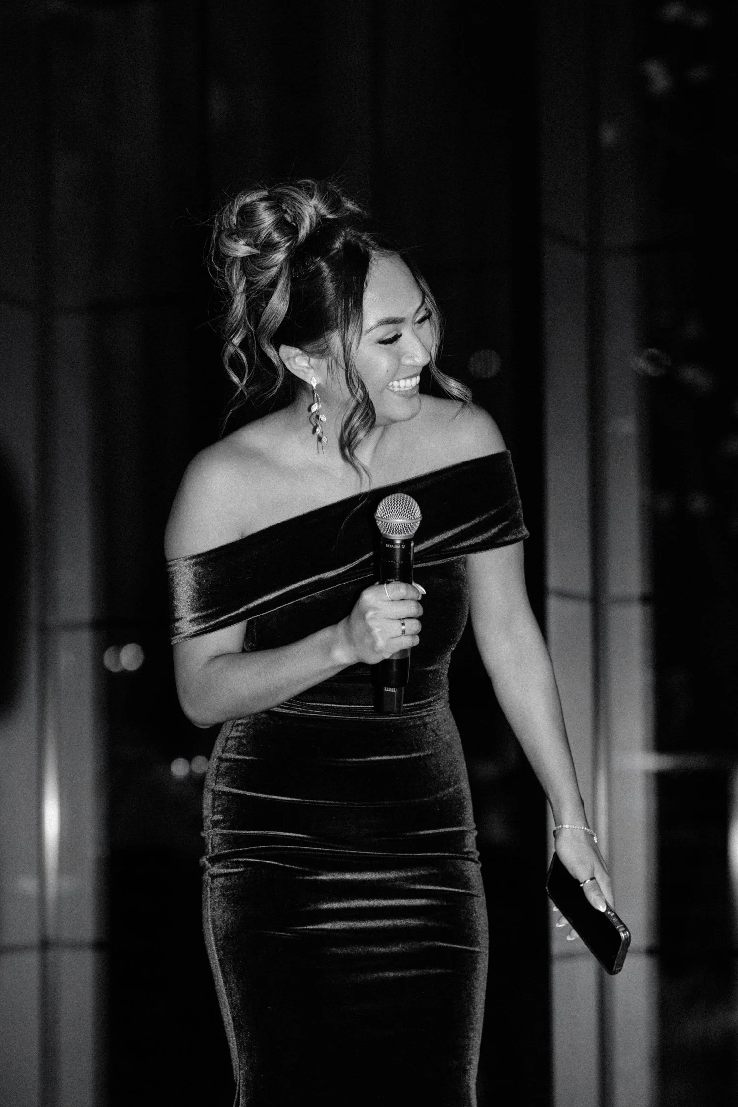 black and white photograph of maid of honor laughing during her speech during wedding reception at the roundhouse