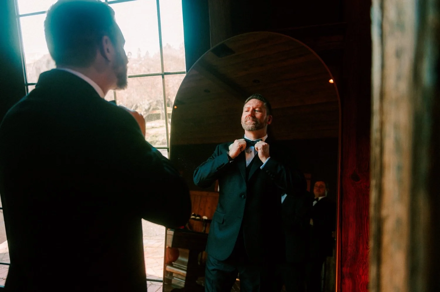 groom tightening bowtie for winter wedding day at the ashford estate