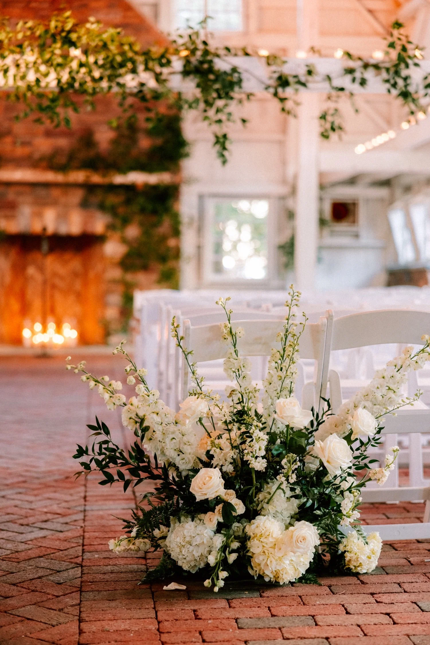 barn wedding ceremony filled with candlelight and flowers for winter wedding day at the ashford estate