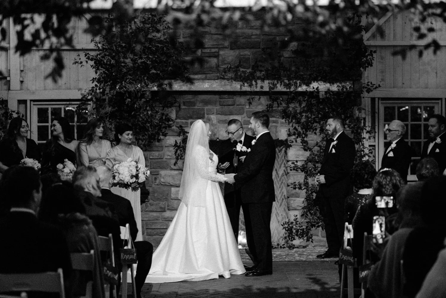 bride and groom holding hands during winter wedding ceremony in barn