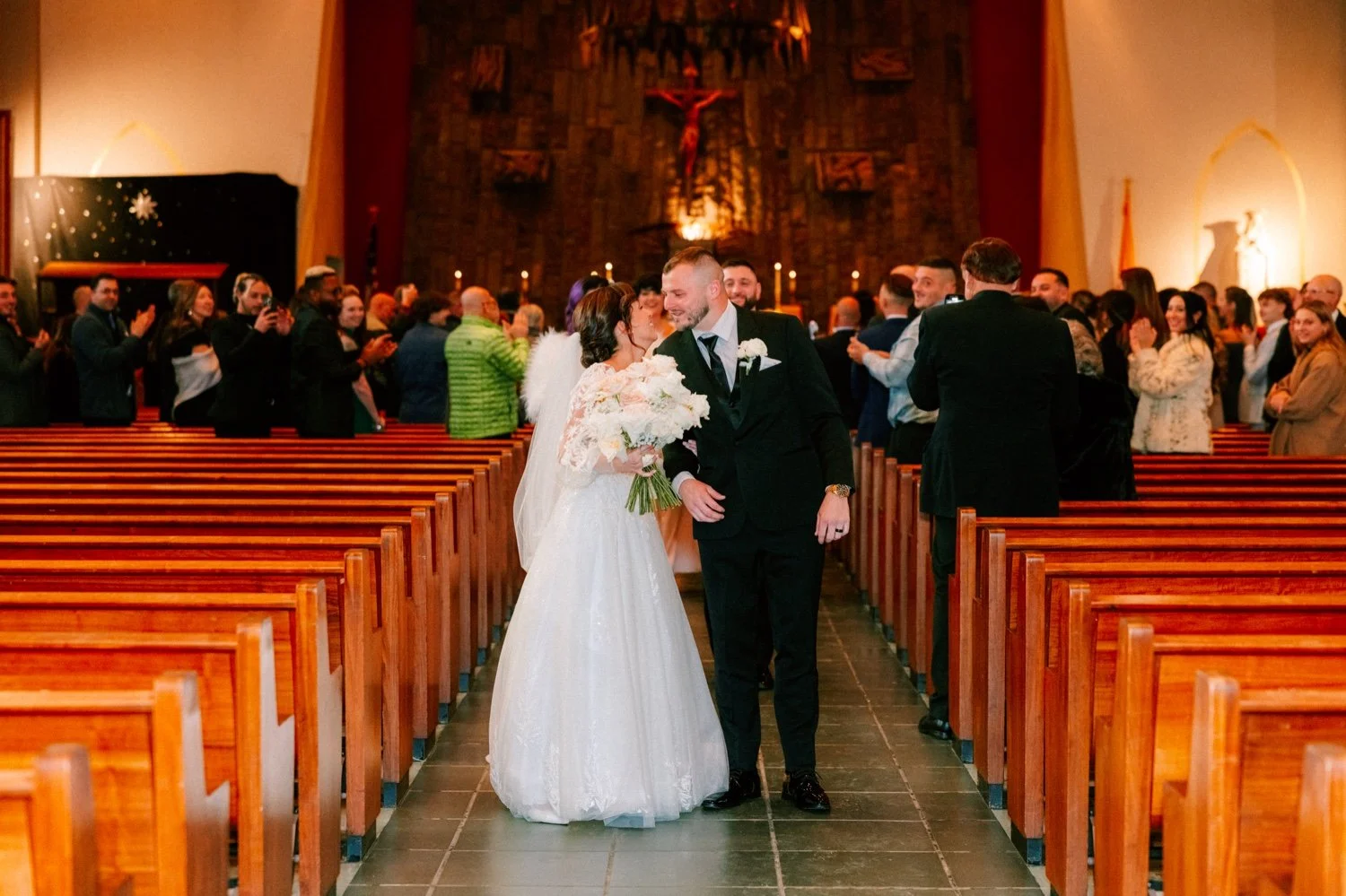  wedding couple kiss in church aisle during their ceremony recessional 
