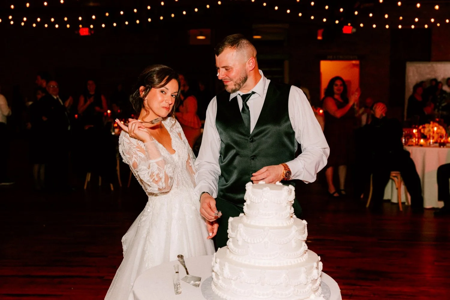  bride looks at camera while grooms looks at her during their cake cutting at city winery hudson valley 