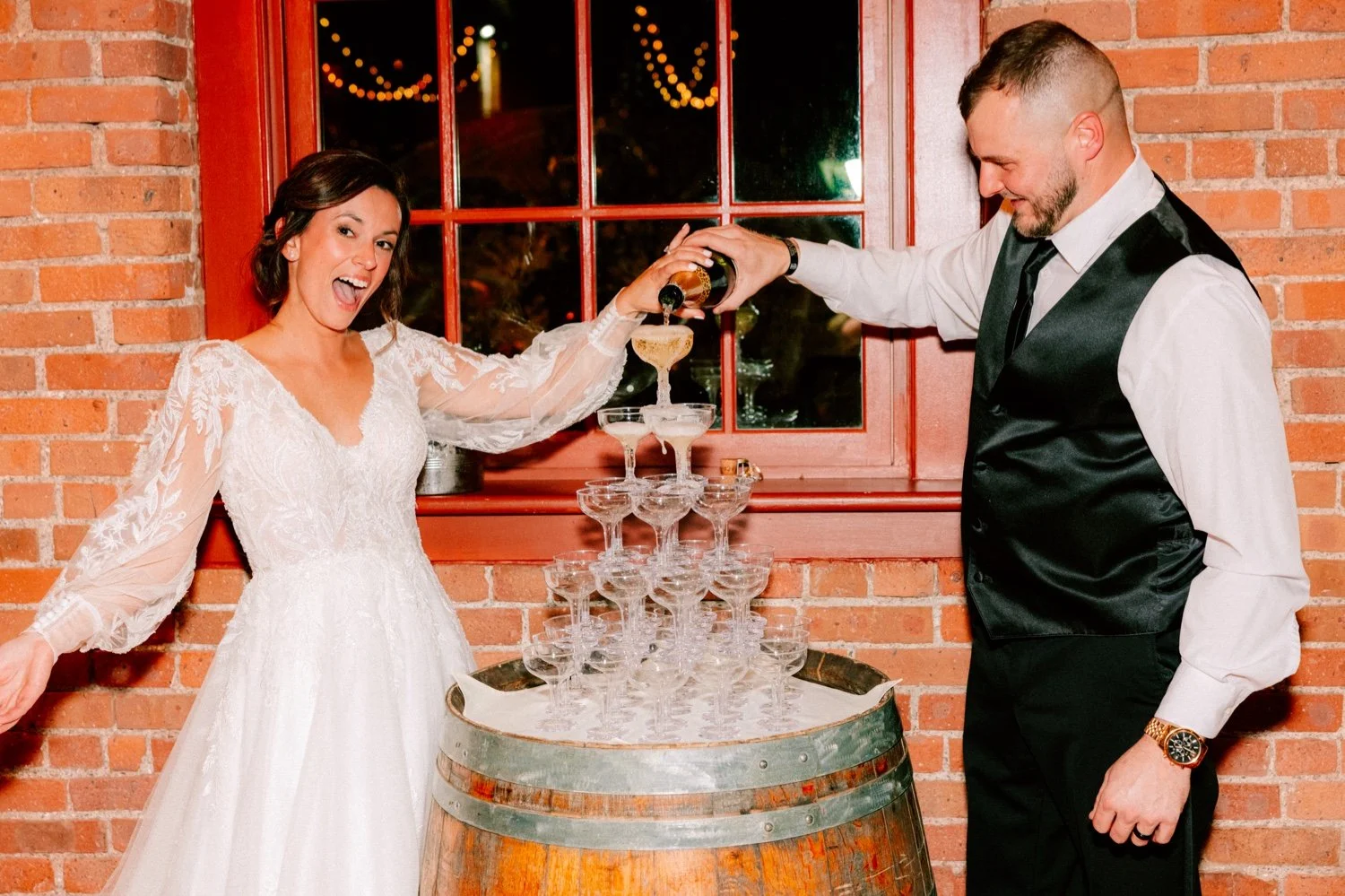  bride looks at camera as her and groom pouring champagne over tower at city winery hudson valley 