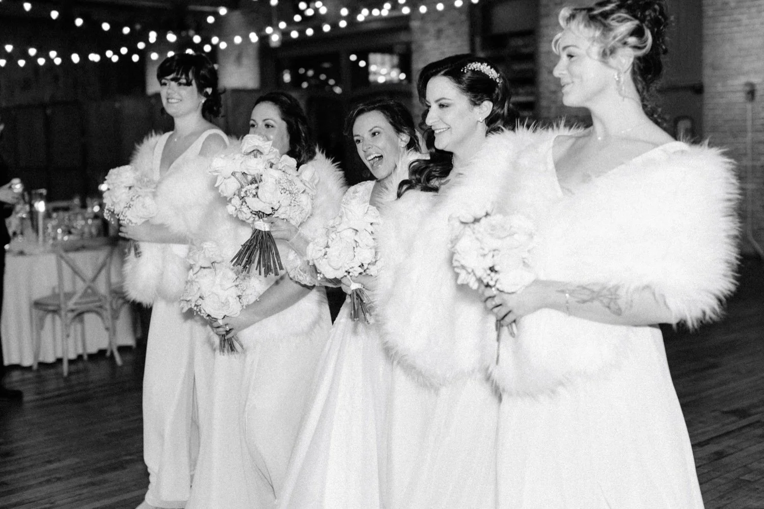  bride and bridesmaids laugh walking inside city winery hudson valley on winter wedding day 
