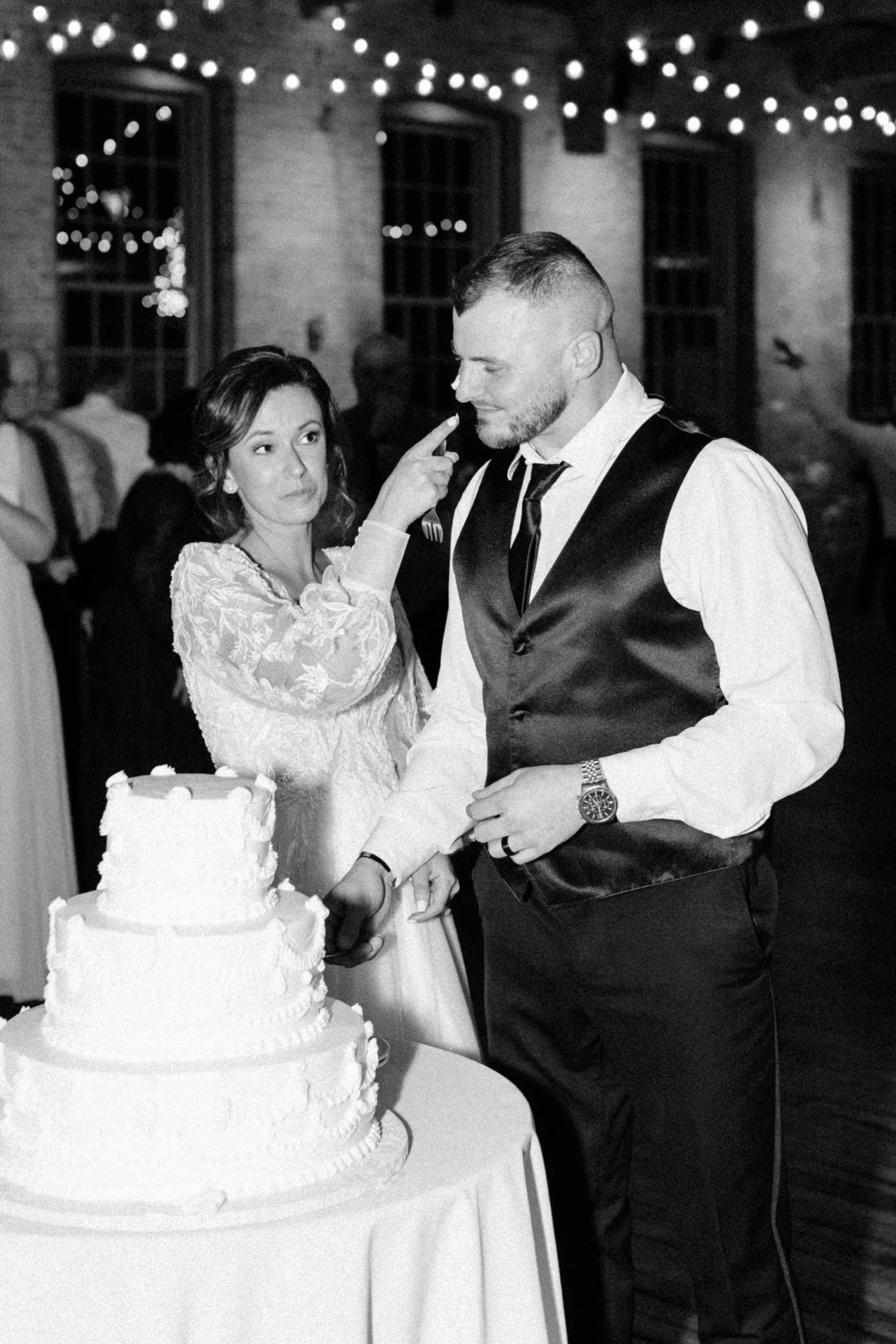  bride rubs frosting on grooms nose while cutting their vintage wedding cake at city winery hudson valley 