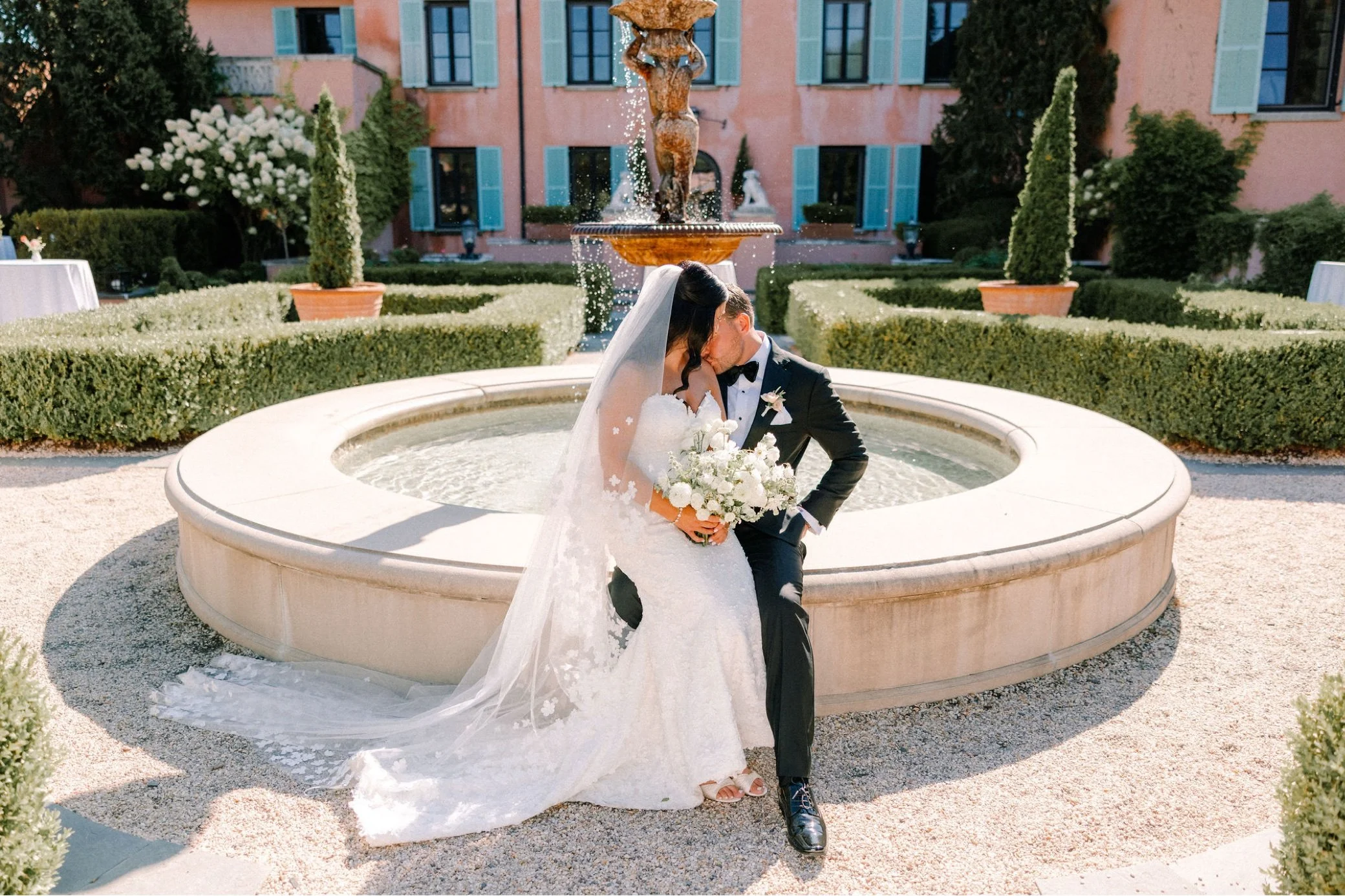  wedding couple sitting on fountain in the garden of glenmere mansion 