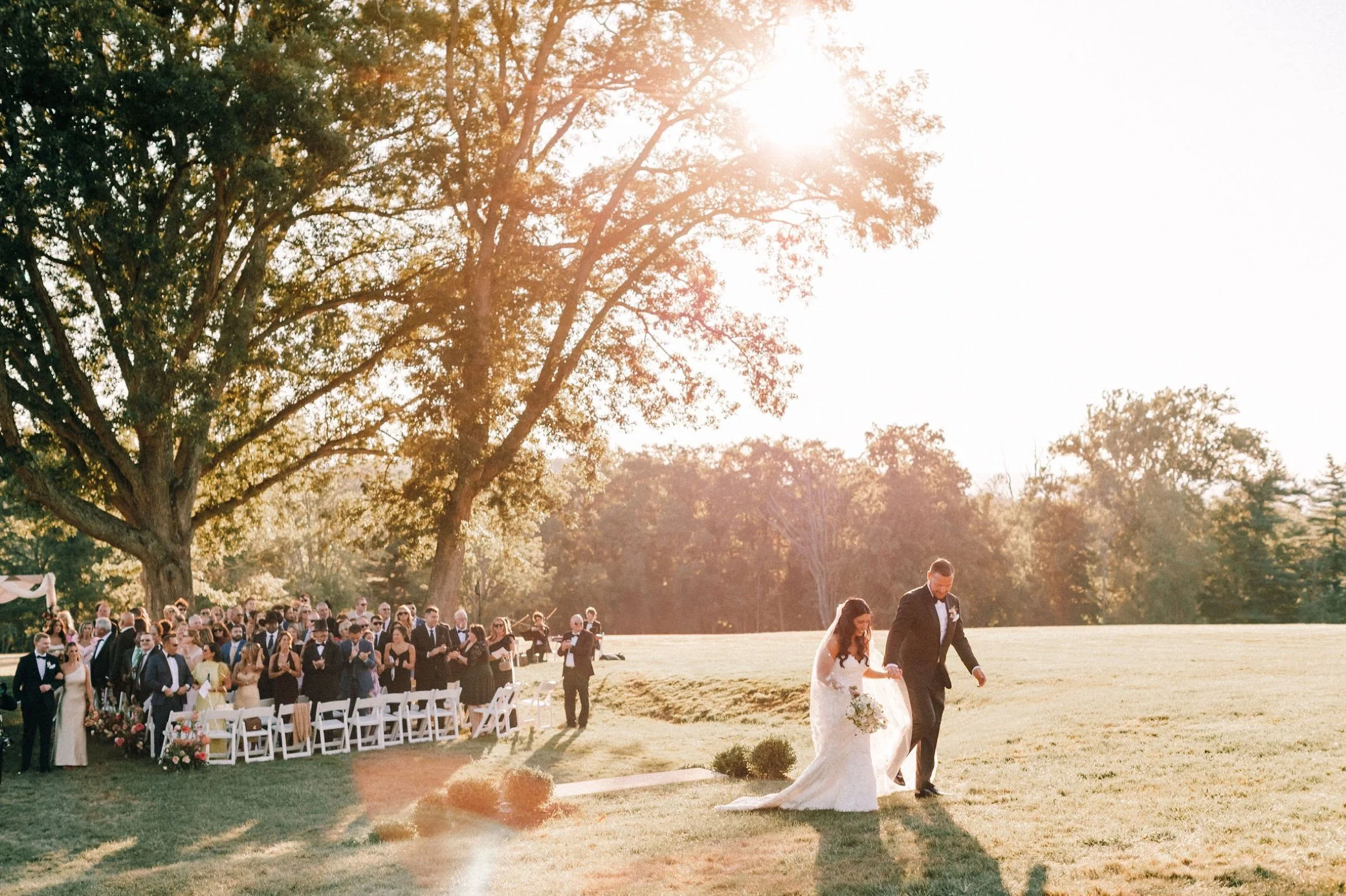  couple walking up lawn after wedding ceremony at glenmere mansion 