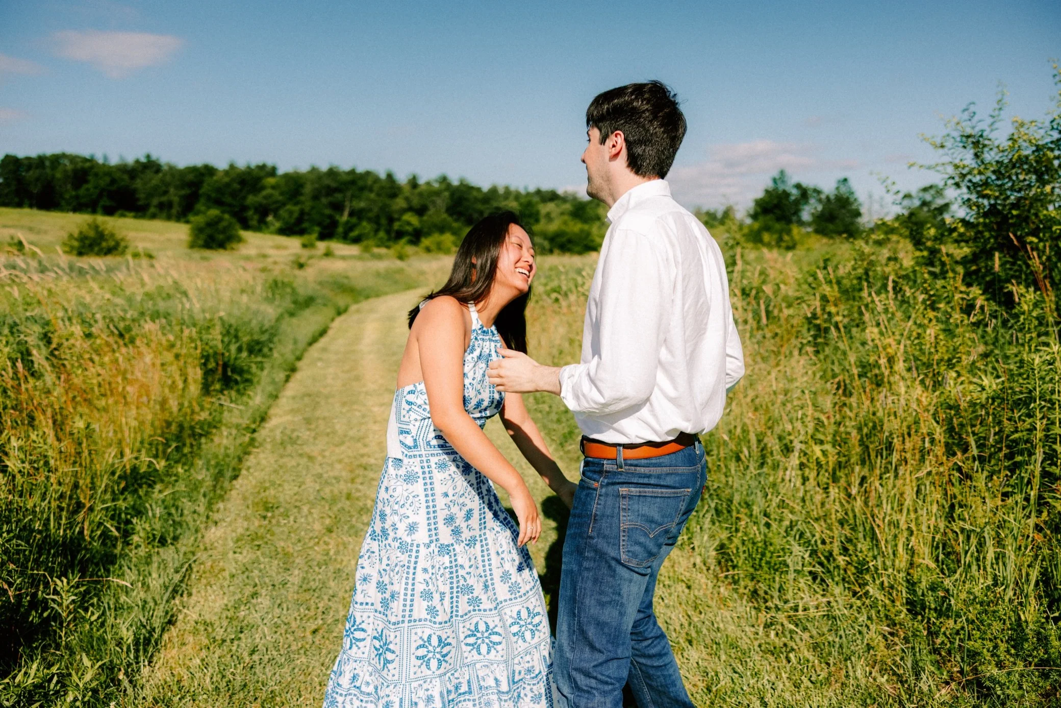  hudson valley engaged couple laugh in a field during in Chatham, NY 